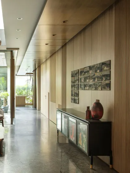 The ground floor corridor features fluted wooden paneling that conceals doors, creating a seamless and elegant look. A custom sideboard displays art, demonstrating how we integrate function and beauty.