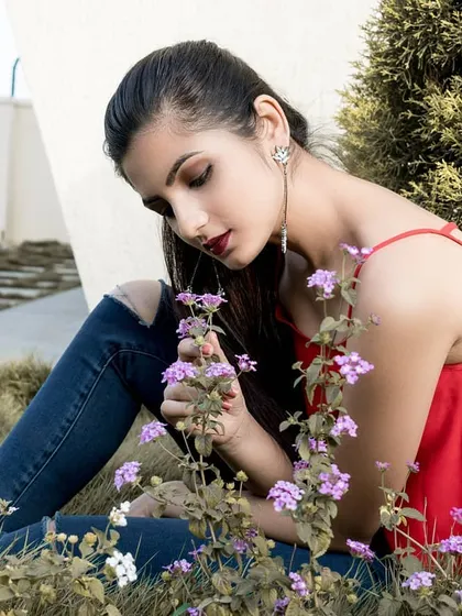 A close-up of the model interacting with the flowers. This shot captures a gentle and serene moment, using the natural garden setting to create a beautiful, faded blossom theme.