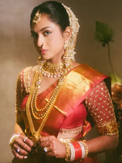A beautiful close-up portrait of a South Indian bride, adorned with layers of traditional gold jewelry. The lighting and composition highlight her radiant beauty.