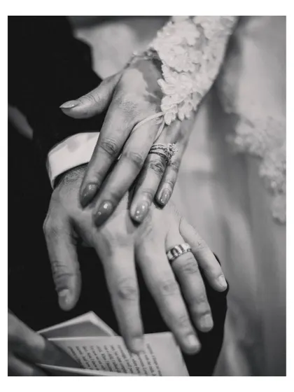 A black and white detail shot of the couple's hands, showing their wedding rings, symbolizing their new union.