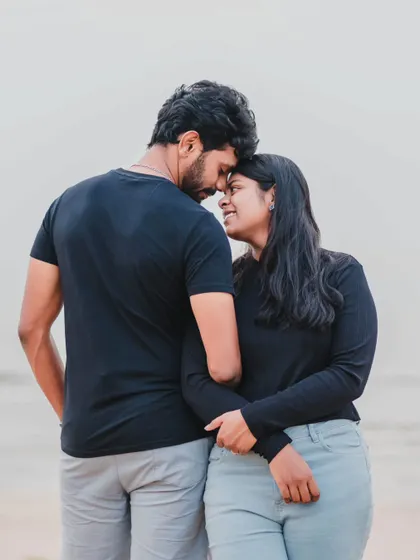 An intimate pose on the sand, capturing the gentle and loving connection between the couple with the sea in the background.