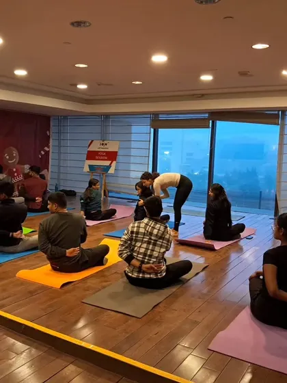 Providing hands on assistance in a corporate yoga class to help an employee find a deeper stretch.
