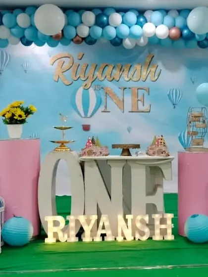 A serene sky and hot air balloon theme for Riyansh's first birthday. I used a sky-blue backdrop, a blue and white balloon arch, and pink pedestals to create a dreamy and gentle look for the celebration.