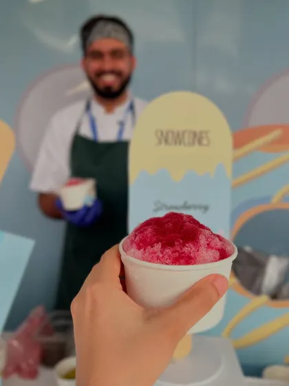 A smiling chef stands behind the snow cone station, ready to serve up a refreshing treat.