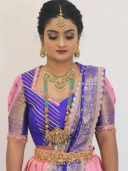 A full look at a beautiful South Indian bride. The makeup is perfectly balanced with her elaborate jewellery and colorful outfit, creating a harmonious and elegant appearance.