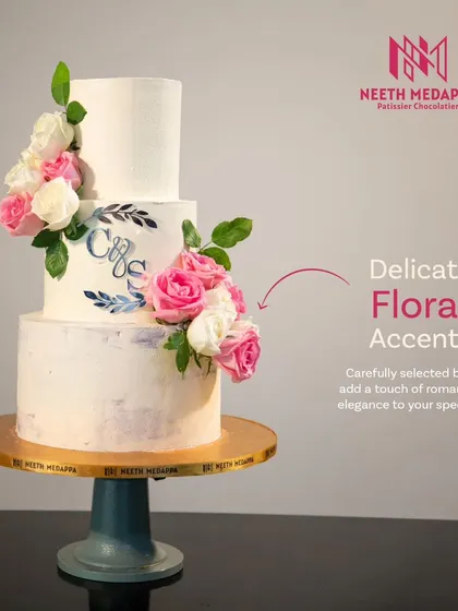 This image highlights the delicate floral accents and personalized monogram on our three-tiered 'Slice of Forever' wedding cake. The soft brushstrokes of color add a subtle, artistic touch.