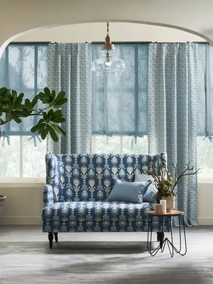 A view through an archway into a living space with a high-backed loveseat. This framing technique creates an intimate and focused composition, drawing the eye to the furniture and fabric patterns.