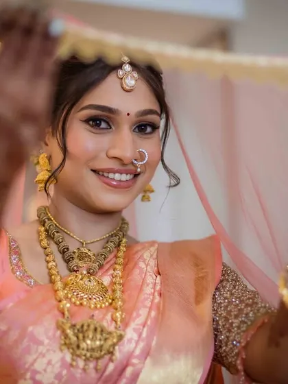 The final reveal. This is the moment the bride is fully ready, holding her veil and smiling, ready to walk down the aisle. A beautiful portrait of a South Indian bride.