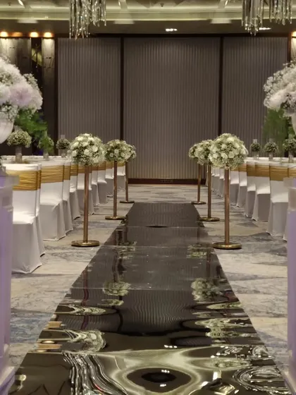 A stunning pathway for a Christian wedding. The aisle is lined with grand white floral arrangements and features a reflective, water-like surface that creates a dramatic and elegant entrance.