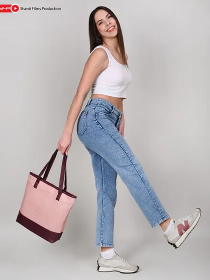 This playful, high-key shot of a model with a canvas tote bag is designed to appeal to a younger demographic. The clean background keeps the focus on the product's color and shape.