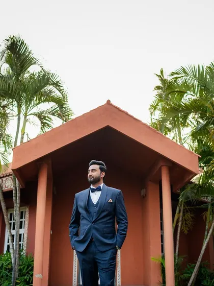 A classic portrait of the groom standing proudly in front of a resort villa at his destination wedding.