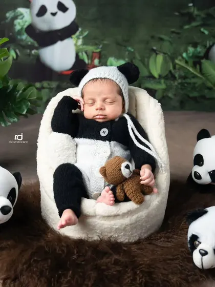A sleepy panda cub holding his tiny teddy bear. The cuteness is just overwhelming.
