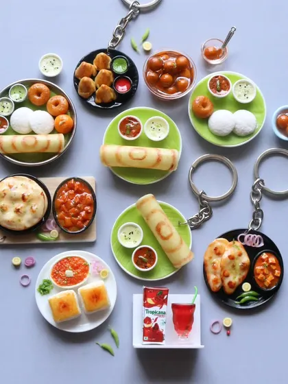 A beautiful arrangement of various food keychains, including dosa, idli, naan, and pav bhaji.