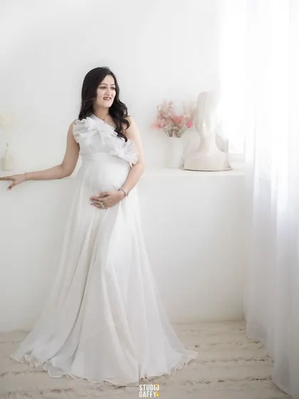 A graceful portrait of the mother-to-be in a flowing white gown, embodying the elegance of pregnancy.