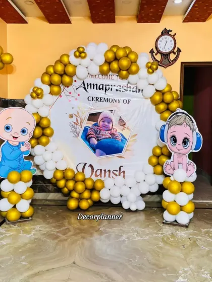 For a more modern take on the Annaprashan ceremony, I designed this beautiful setup with a gold and white balloon arch. The personalized backdrop featuring the baby's photo adds such a sweet, personal touch to this special milestone.