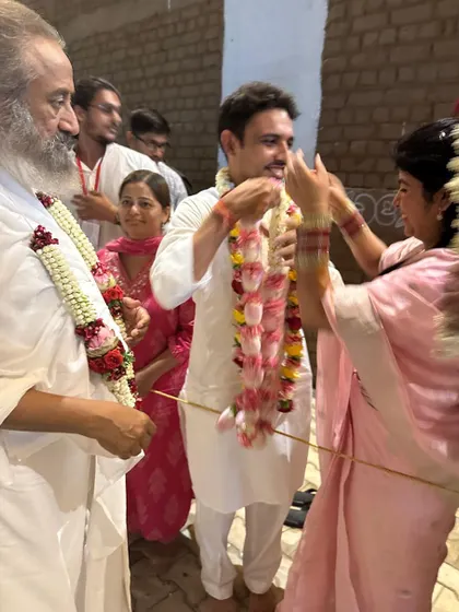 Here, Richa and Puneet participate in the garland exchange ceremony, a pivotal moment in a Hindu wedding. This simple ritual, witnessed by Gurudev, signifies their mutual acceptance and the beginning of their shared life.