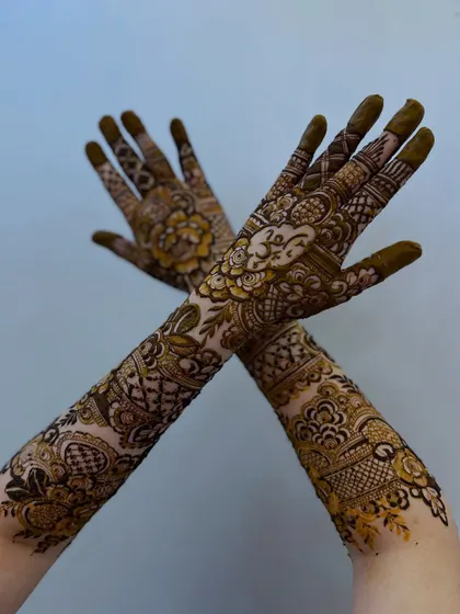 The crossed-hands pose showcases the beautiful symmetry and flow of this custom designer floral henna.