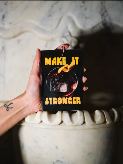 "Make it Stronger." A custom-designed coaster from Negroni Week, held against our marble fountain. It's all about the details.