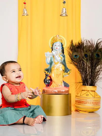 A candid moment of a baby girl looking up at a Krishna statue during our Janmashtami session. We create a reverent and joyful atmosphere for these special shoots.