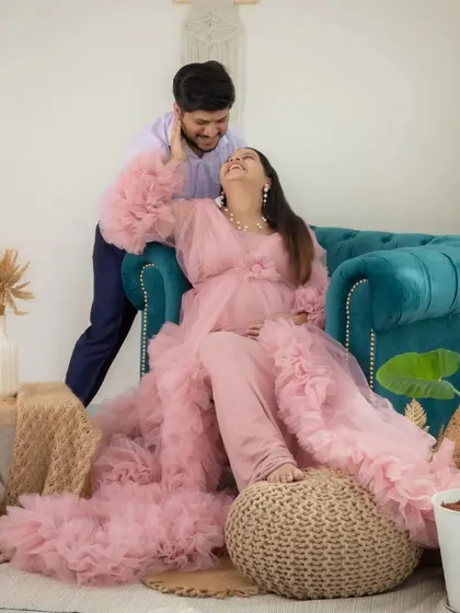 A candid and joyful moment from a studio lifestyle session. The couple shares a laugh, creating a natural and happy memory of their pregnancy.