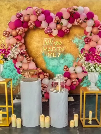 Make a bold statement with a custom balloon heart arch. This vibrant display in shades of pink and rose gold, complete with a "Will you Marry Me?" neon sign, creates a fun and festive backdrop for a memorable proposal.