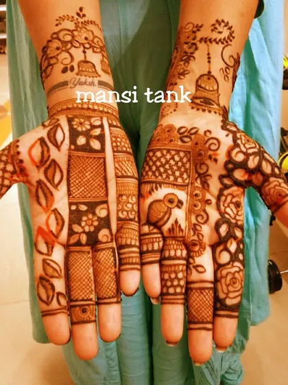 A unique designer mehendi that mixes different styles. It combines grids, bold leaves, floral patterns, and even a small bird and jhumka (earring) motif.