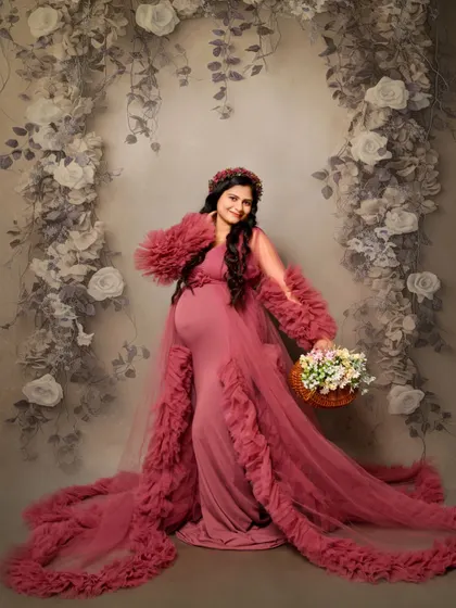 A lovely solo portrait in a dusty rose ruffled gown, set against a grey floral backdrop. The mom-to-be holds a basket of flowers, adding a charming and gentle touch.