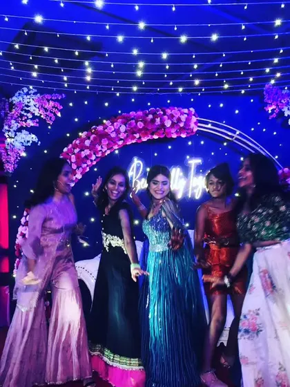 Getting high on dance. This photo captures the pure energy and fun of a sangeet night, with friends dancing under beautiful floral and light decorations.