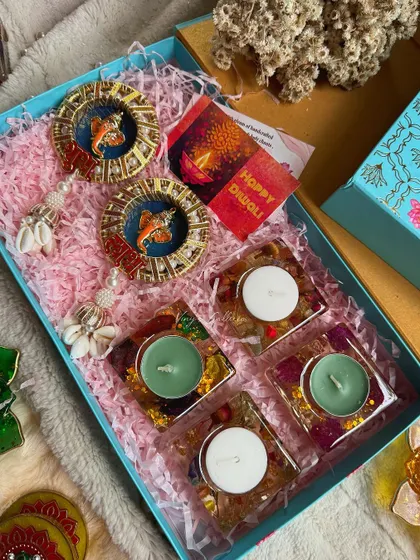 This Diwali hamper includes square floral tealight holders and fish-themed "Shubh Labh" hangings.