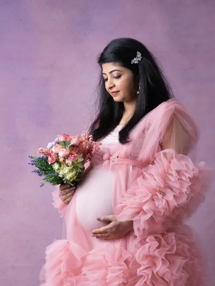 Another beautiful shot from the pink gown maternity session. The makeup is soft and feminine, with a focus on creating a flawless, radiant complexion.