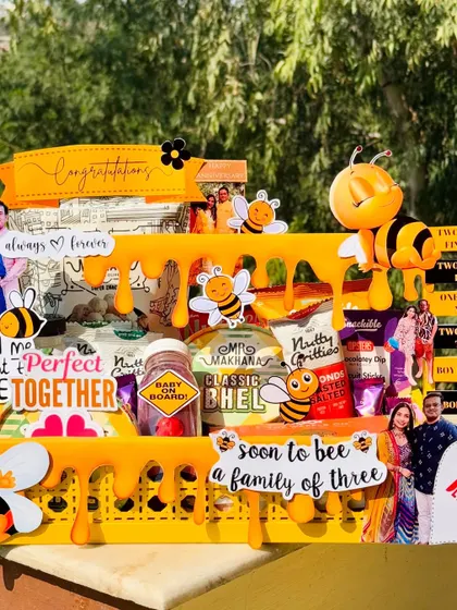 A detailed shot of the "Soon to Bee a Family of Three" hamper, showing the personalized photos and cute bee-themed decorations. It’s a perfect gift to celebrate a couple's anniversary and pregnancy.