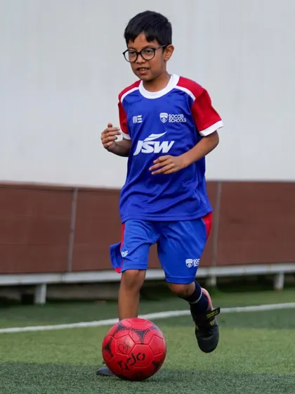A young player dribbles with a smile, showing the pure enjoyment of the game. Our goal is to make every session a positive and fun experience.