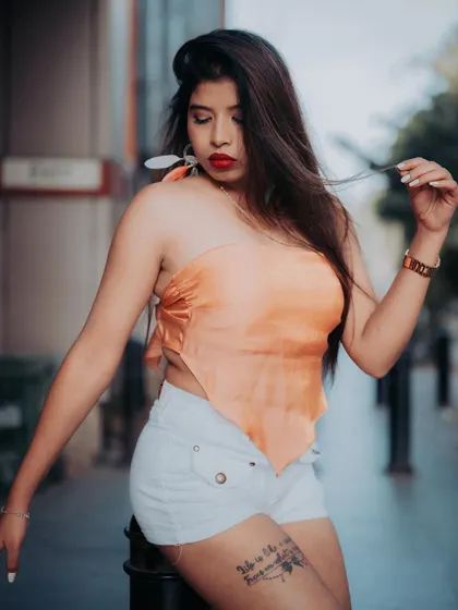 A portrait of a model in a casual outfit, leaning against a post. The urban setting and her confident pose make this a great street style shot.