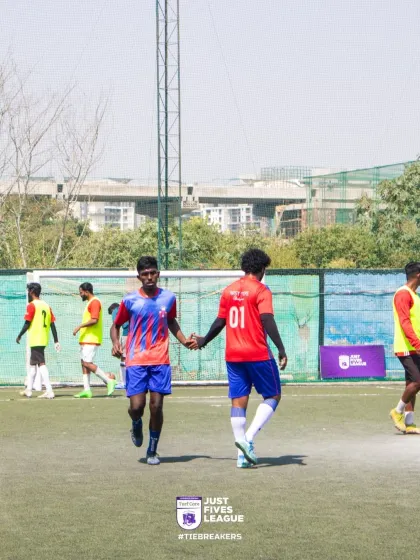 Two players in red jerseys share a supportive handshake during a break in play. These moments of connection are at the heart of our team-building events.