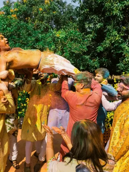 The groom is tossed in the air by his friends during a wild and colorful Holi-themed celebration.