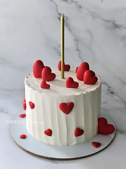 Little red hearts everywhere. A season-special mango cake with a simple, rustic finish and scattered red hearts.