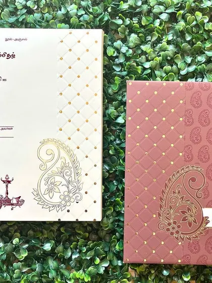 A traditional Tamil wedding invitation featuring a paisley motif. The text is beautifully printed in Tamil script on the envelope.