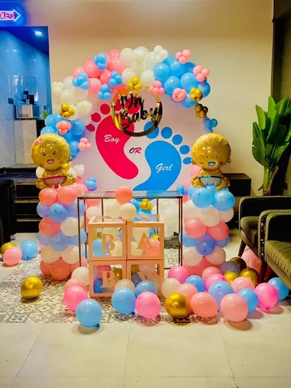 This full view shows a complete gender reveal party setup in a restaurant or hall. The backdrop, balloon pillars, and scattered balloons on the floor create an immersive and exciting atmosphere for the big reveal.