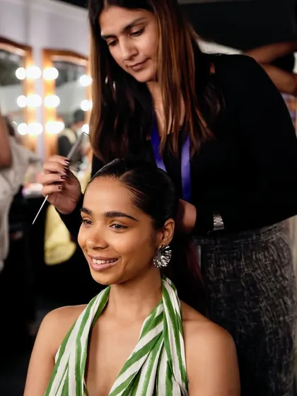 A student styles a model's hair backstage at Lakme Fashion Week. These opportunities allow our artists to work on diverse hair types and create professional runway looks.