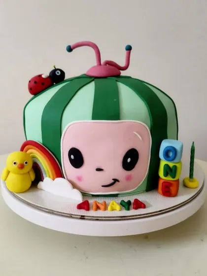 A Cocomelon-themed cake for a first birthday. This sculpted cake looks just like the iconic character, complete with a little ladybug and rainbow.