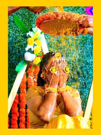 An artistic shot of the bride being showered with turmeric and flowers during her Haldi ceremony.