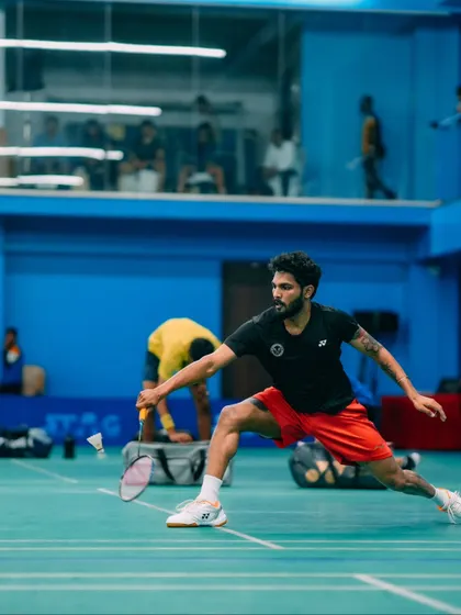 A low lunge to save the point. This player demonstrates incredible flexibility and determination, key attributes of a competitive badminton player.