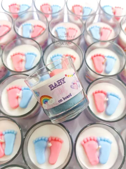 A personalized 'Baby on Board' votive candle held in hand, showing the custom rainbow-themed sticker created for Megha's baby shower.