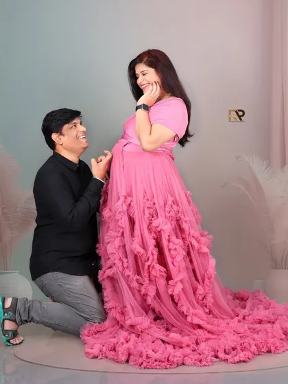 A playful and loving moment. The dad-to-be kneels before his partner, sharing a happy and intimate moment during their maternity session.