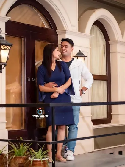 A sweet, candid moment captured on a studio set designed to look like a city street at night. The warm glow from the street lamps adds to the romantic ambiance.