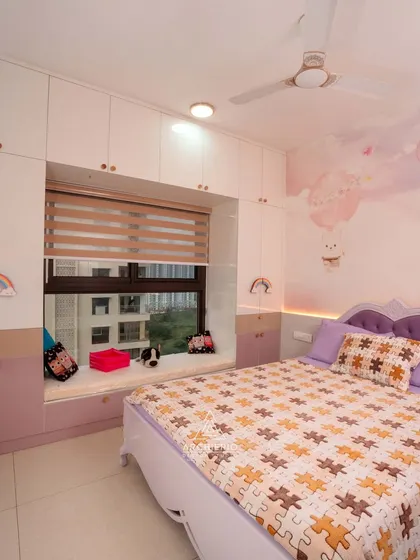 A lovely kids' room with a bay window seat surrounded by storage cabinets. The whimsical wall mural and puzzle-themed bedding add a playful and personal touch.