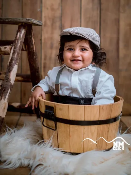 A handsome little man in a bucket. We use simple, rustic props like this wooden bucket and flat cap to create timeless portraits for baby boys.