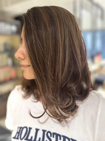 A beautiful transition from red to a warm caramel balayage blend. This mid-length cut shows how a new color can completely transform your style.