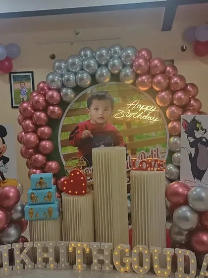 A complete view of the personalized first birthday setup for Likhithgouda. The metallic pink and silver balloons complement the cartoon theme perfectly.
