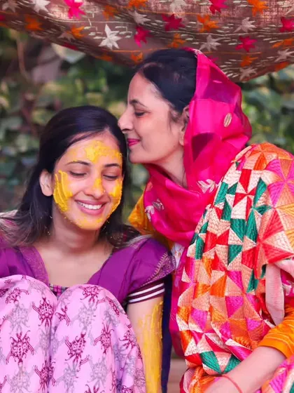 A tender moment between mother and daughter at the Haldi ceremony. A gentle kiss on the cheek captures their close bond on this special day.